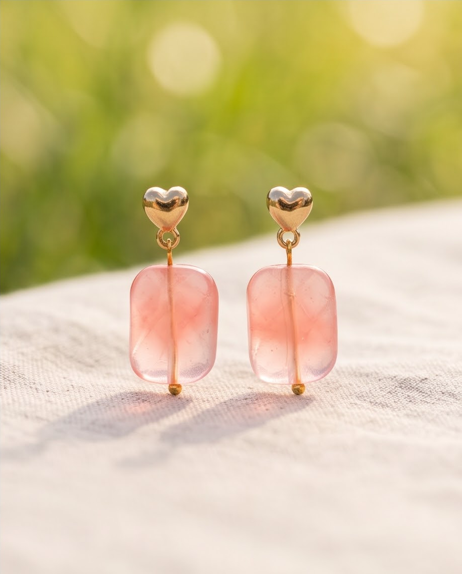 Model laughing in field wearing gold puffed heart stud and pink stone drop earrings