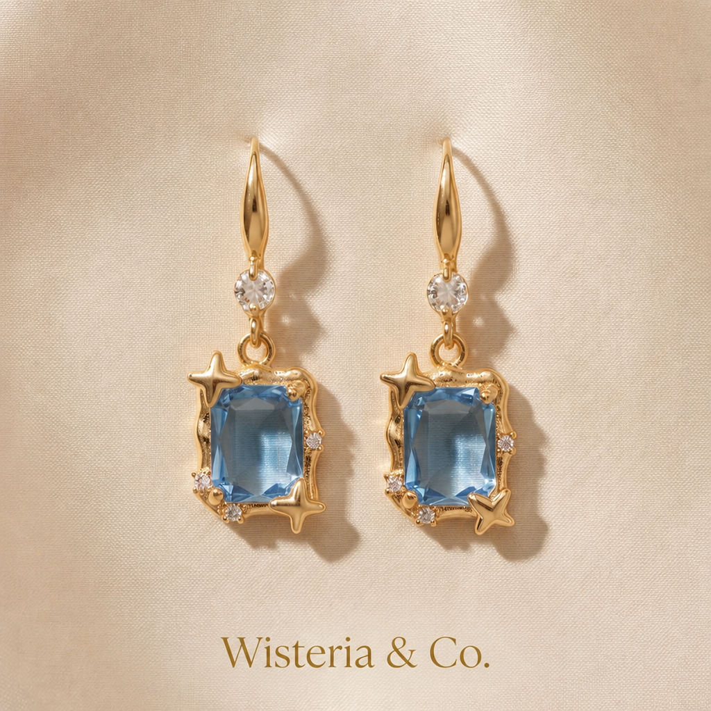 Gold Star Frame Blue Crystal Drop Earrings — Wisteria & Co. branded product shot on gold silk
