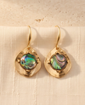 Close-up of iridescent abalone stone set in hammered gold disc earring