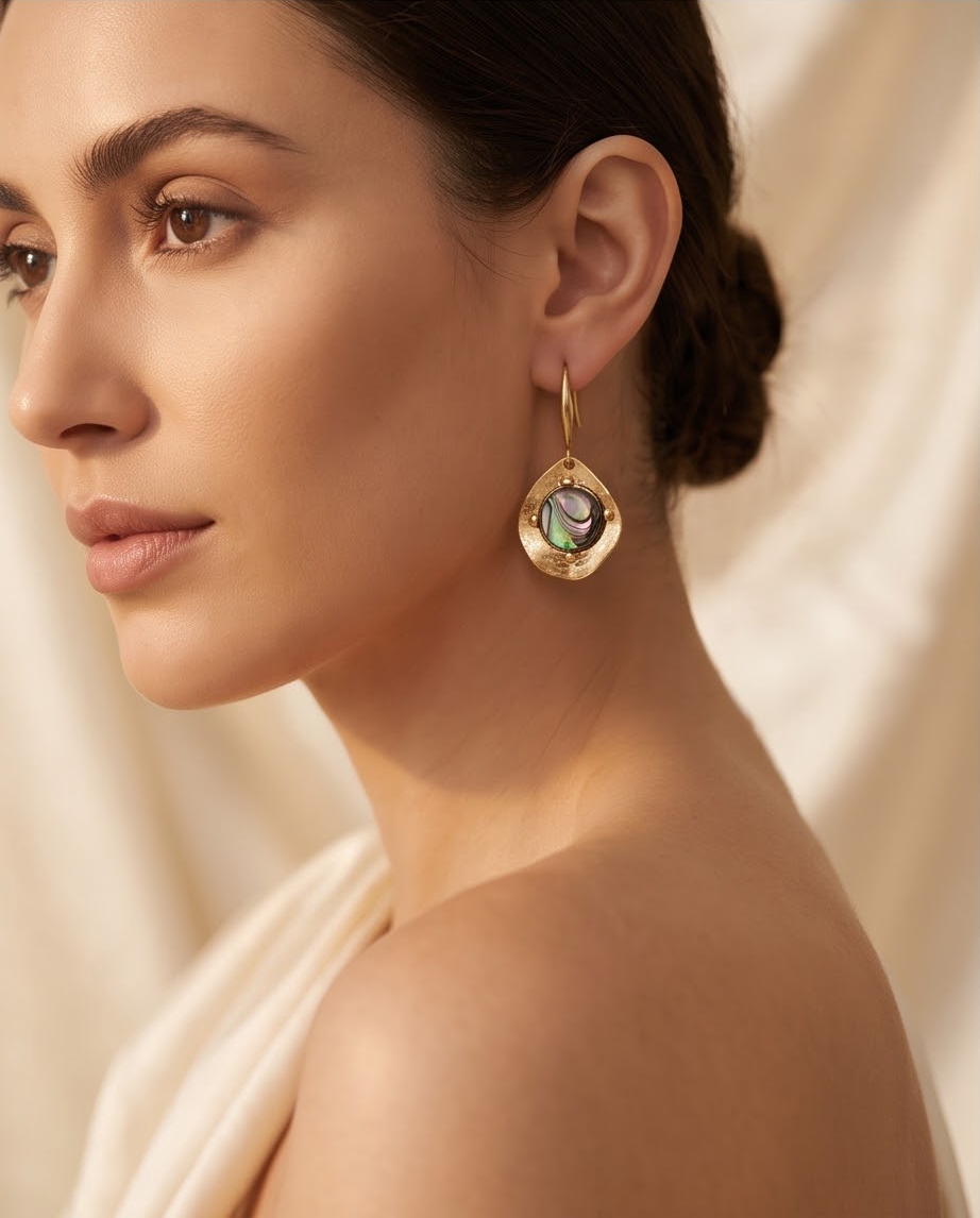 Pair of gold hammered abalone drop earrings flat lay on linen
