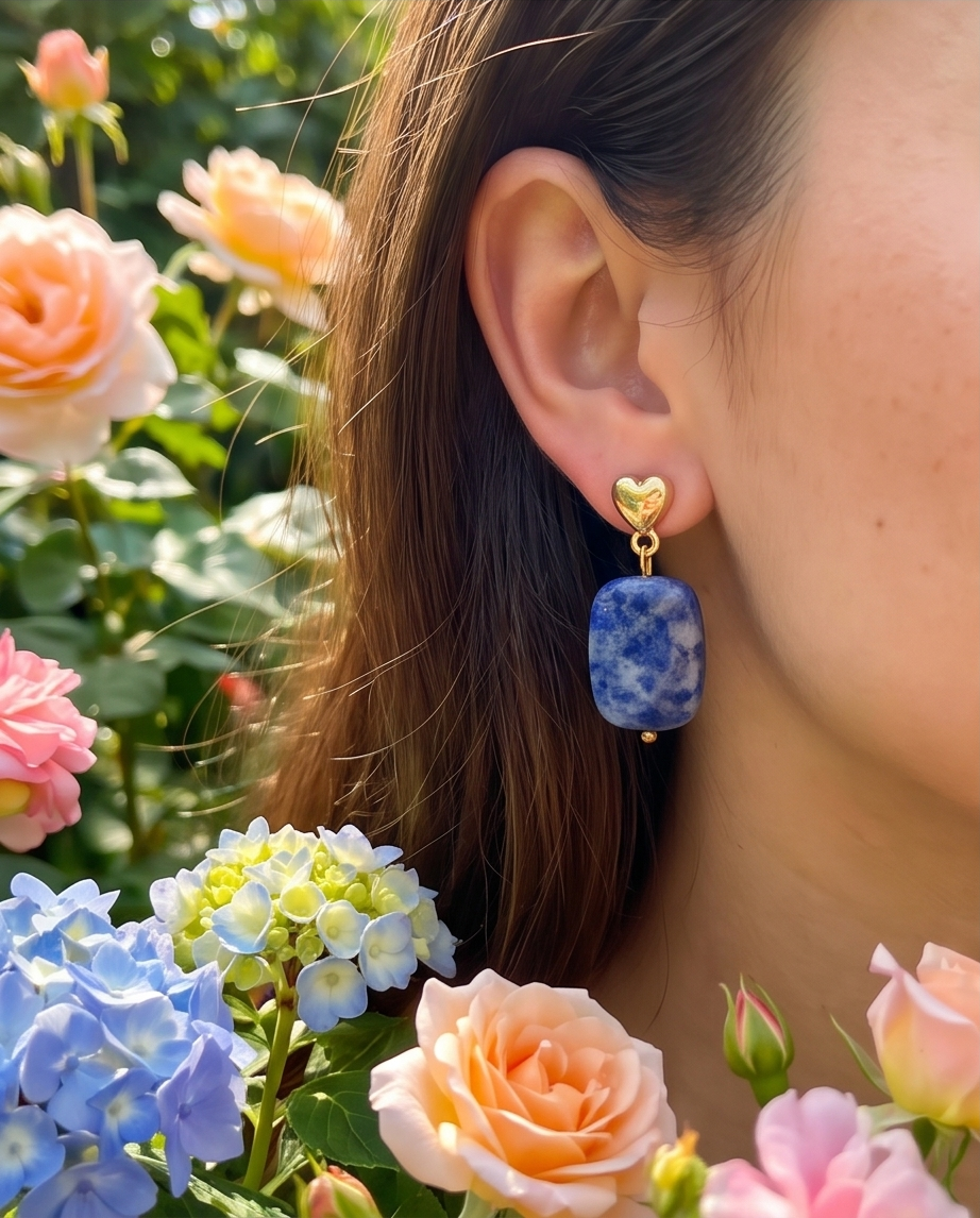 Model wearing gold heart stud sodalite drop earrings surrounded by roses and hydrangeas