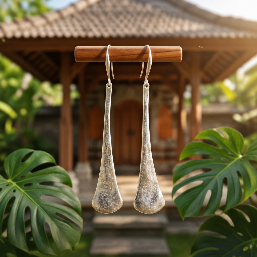 Model wearing silver etched elongated teardrop drop earrings in tropical garden setting