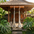 Model wearing silver etched elongated teardrop drop earrings in tropical garden setting