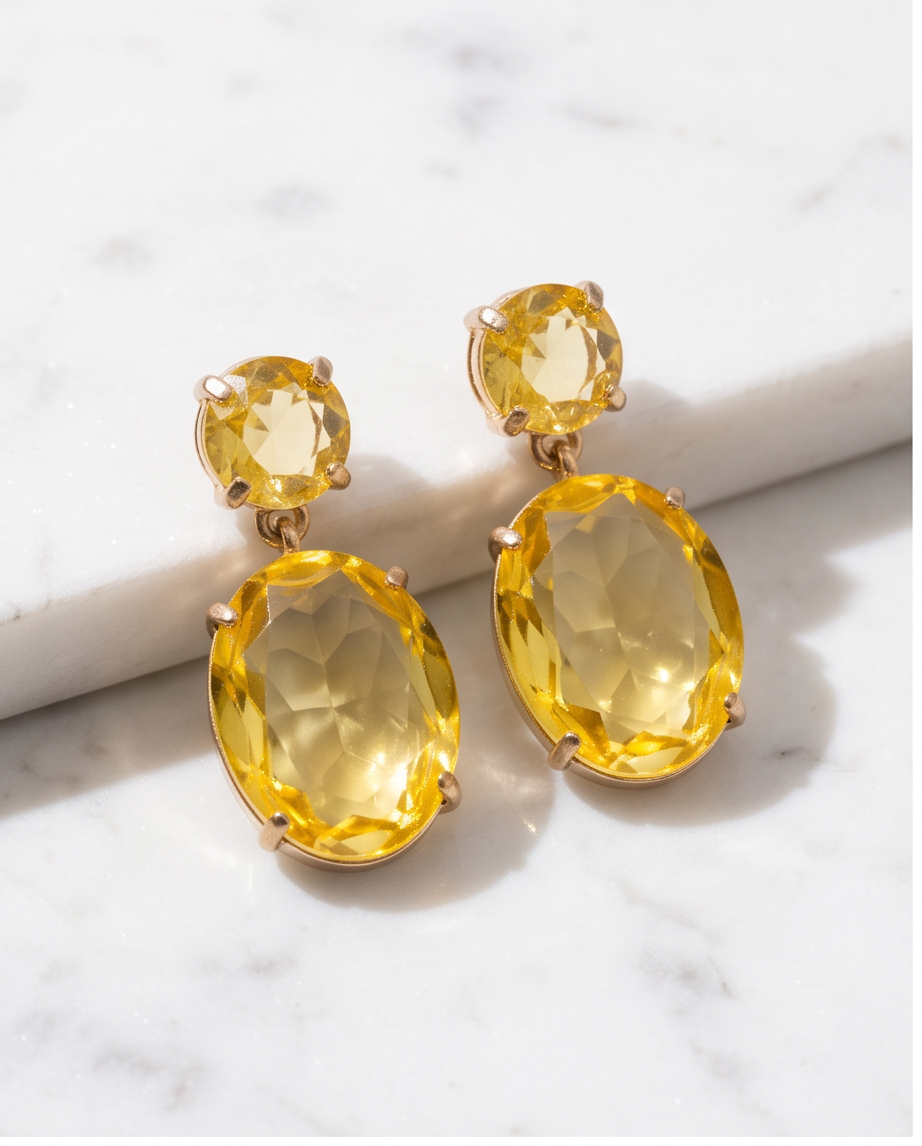 Pair of gold citrine crystal double drop earrings on white marble surface