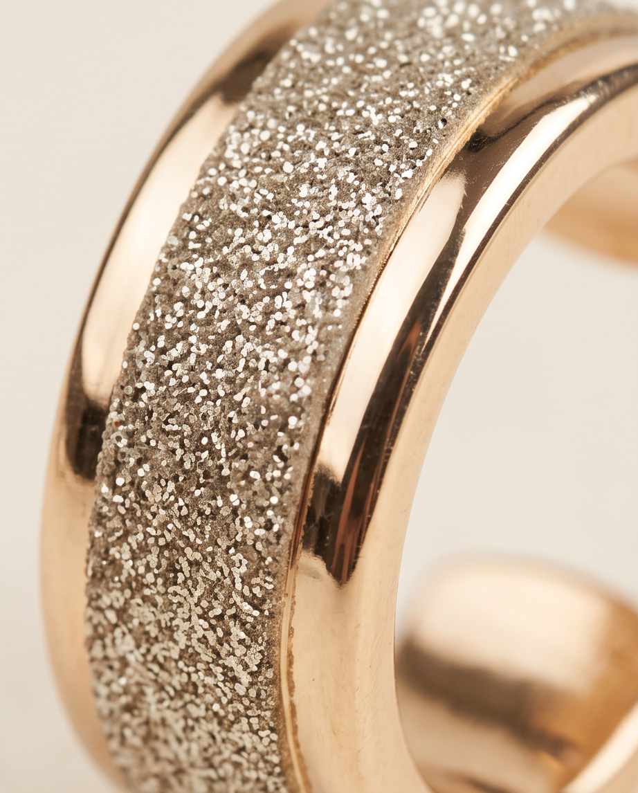 Close-up macro detail of glitter textured centre band and polished gold ridges on chunky hoop earring