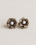 Pair of antique gold textured flower and pearl stud earrings on white surface
