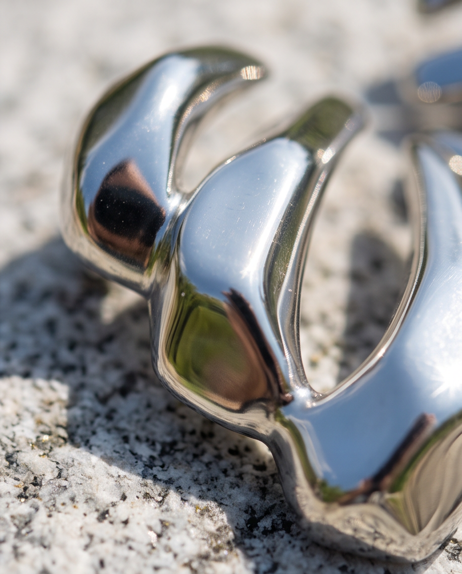 Close up macro shot of polished silver tone sculptural abstract earring detail on stone