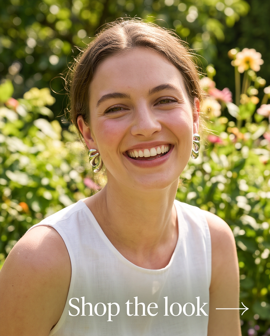 Model smiling in garden wearing silver tone sculptural abstract stud earrings