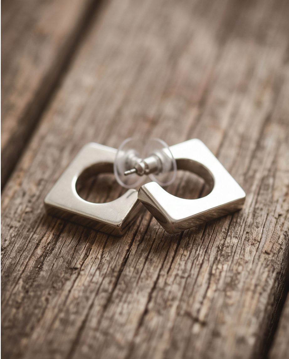Pair of silver tone polished square open hoop stud earrings on natural linen with dried eucalyptus sprigs