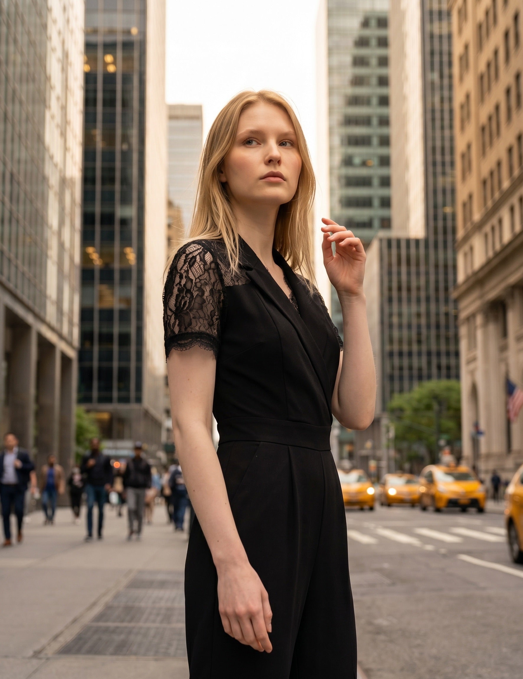Woman in a black dress standing on a city street with tall buildings in the background
