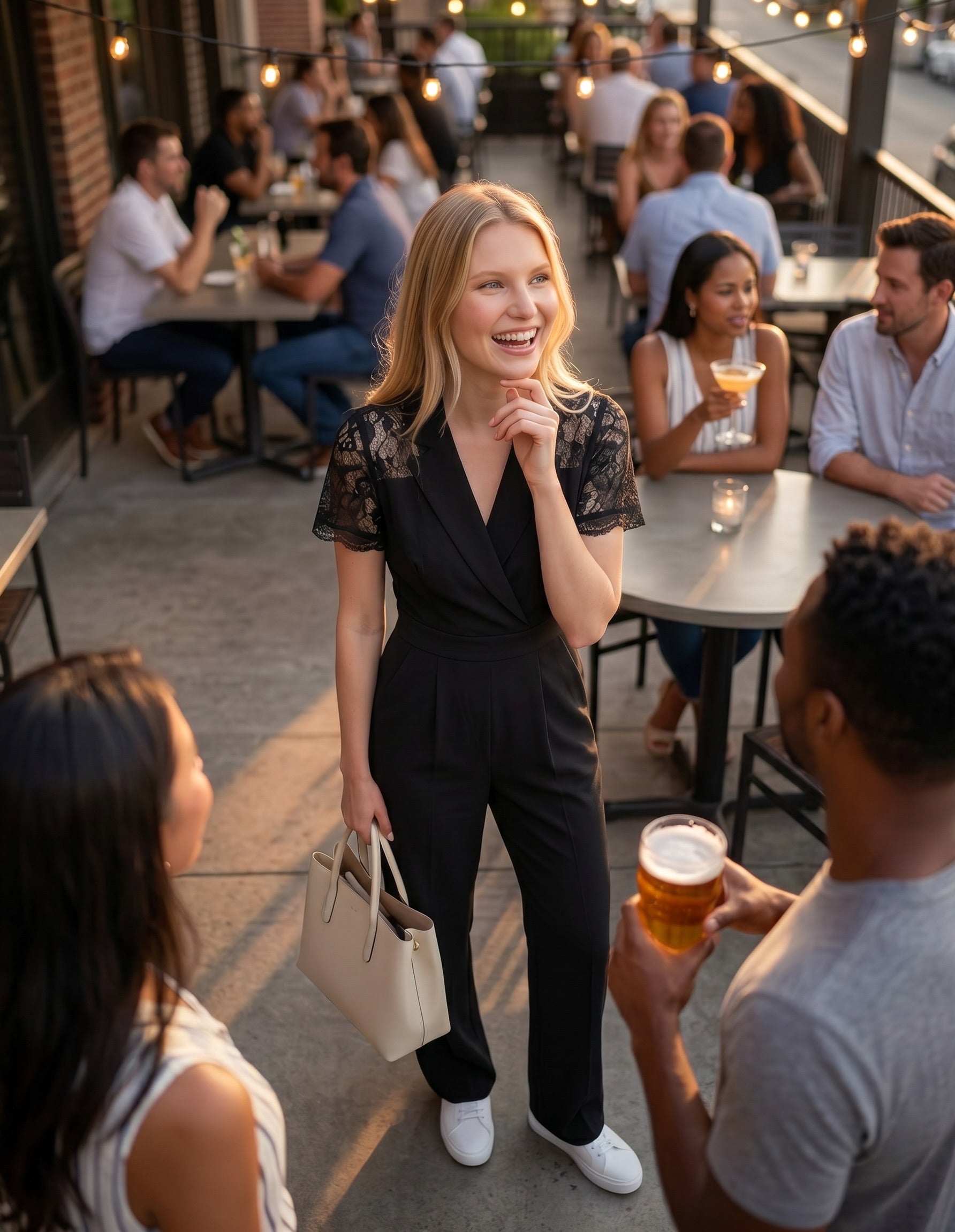 Woman in a black outfit holding a drink in an outdoor social setting