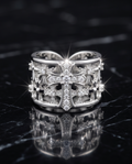 Silver Crystal Cross Wide Band Ring on black marble surface with sparkling light reflections
