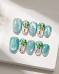 Tropical palm tree shimmer press-on nails flatlay with seashells, tan leather wallet and gold mirror by pool