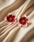 Macro close-up of red and white enamel cherry blossom flower stud earring with gold stamen detail