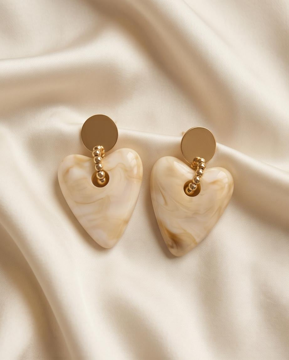 Cream marble heart drop earrings held in hand