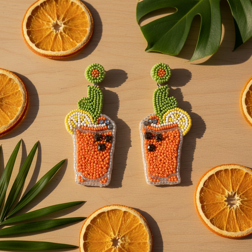 Beaded orange cocktail glass earrings with green cactus leaf and citrus garnish, summer staging shot